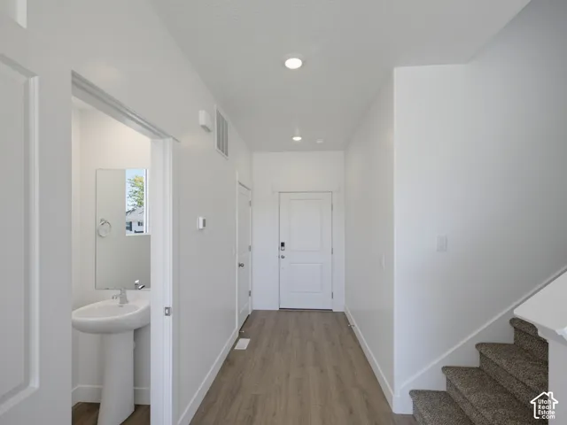 Entryway featuring wood-finish flooring, recessed lighting, white panel doors, and a carpeted staircase