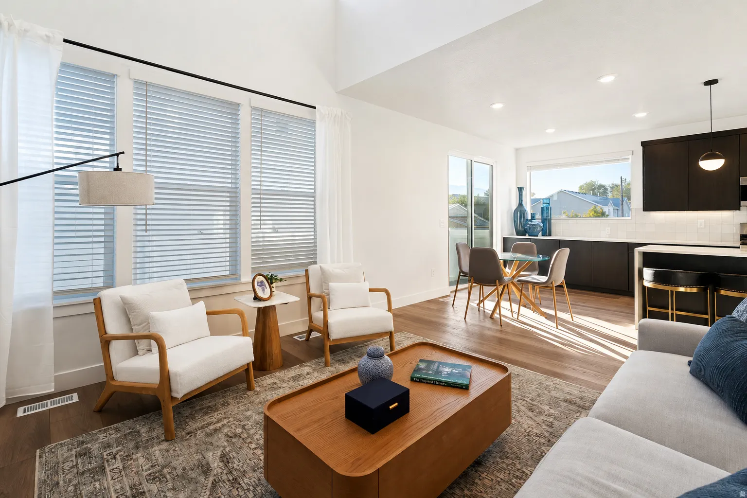 Vaulted ceilings, wood-finish flooring, recessed lighting, expansive windows, and a built-in kitchen island with seating