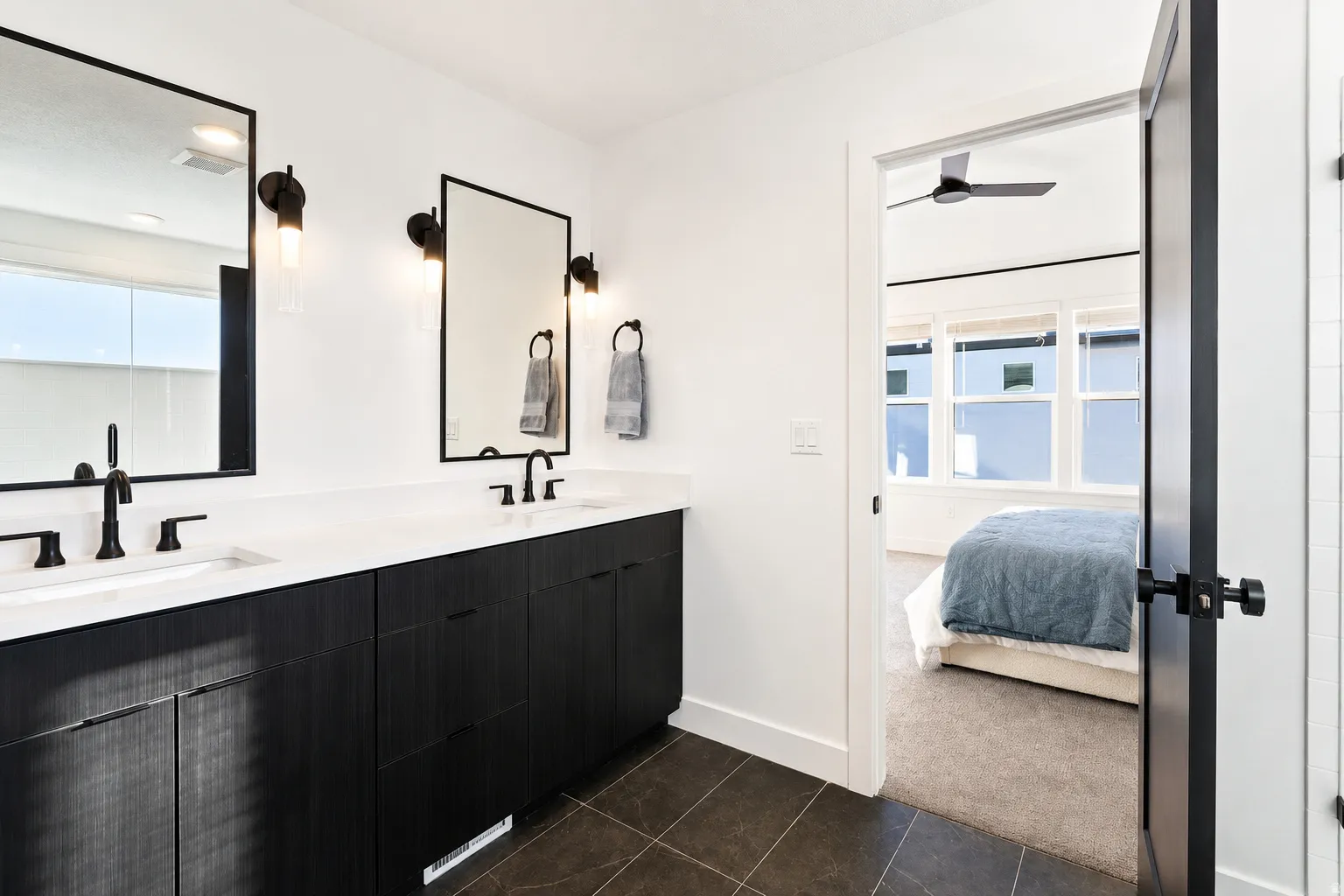 Dual vanity with dark wood-finish cabinetry, white countertop, and matte black fixtures