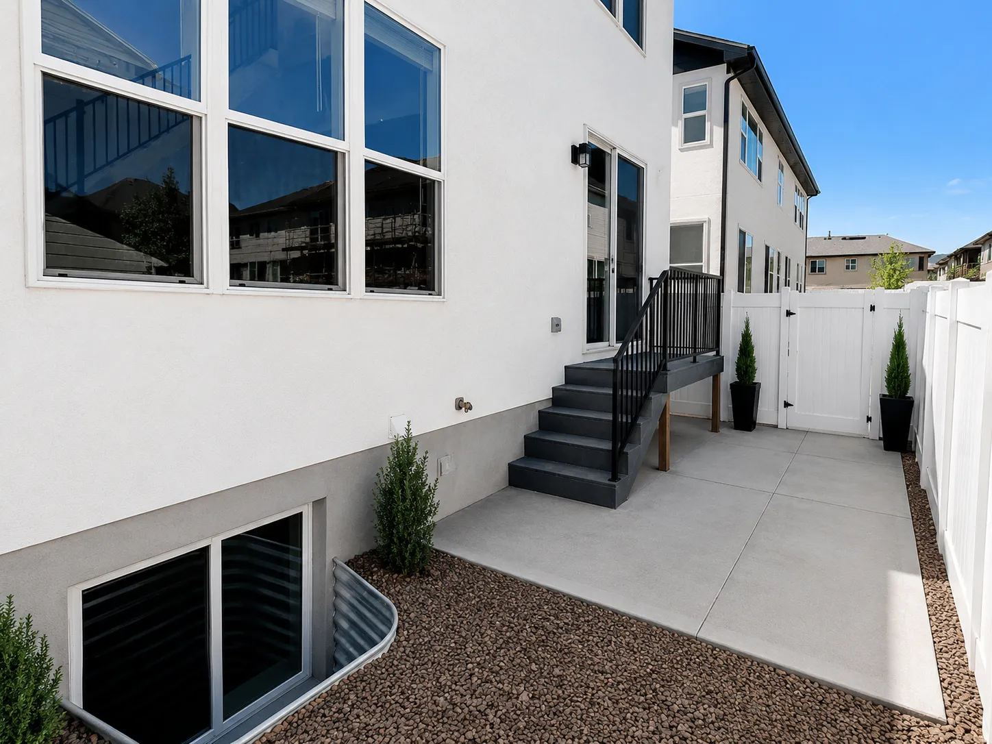 Private outdoor patio featuring a concrete surface, white vinyl fencing, and a separate gate