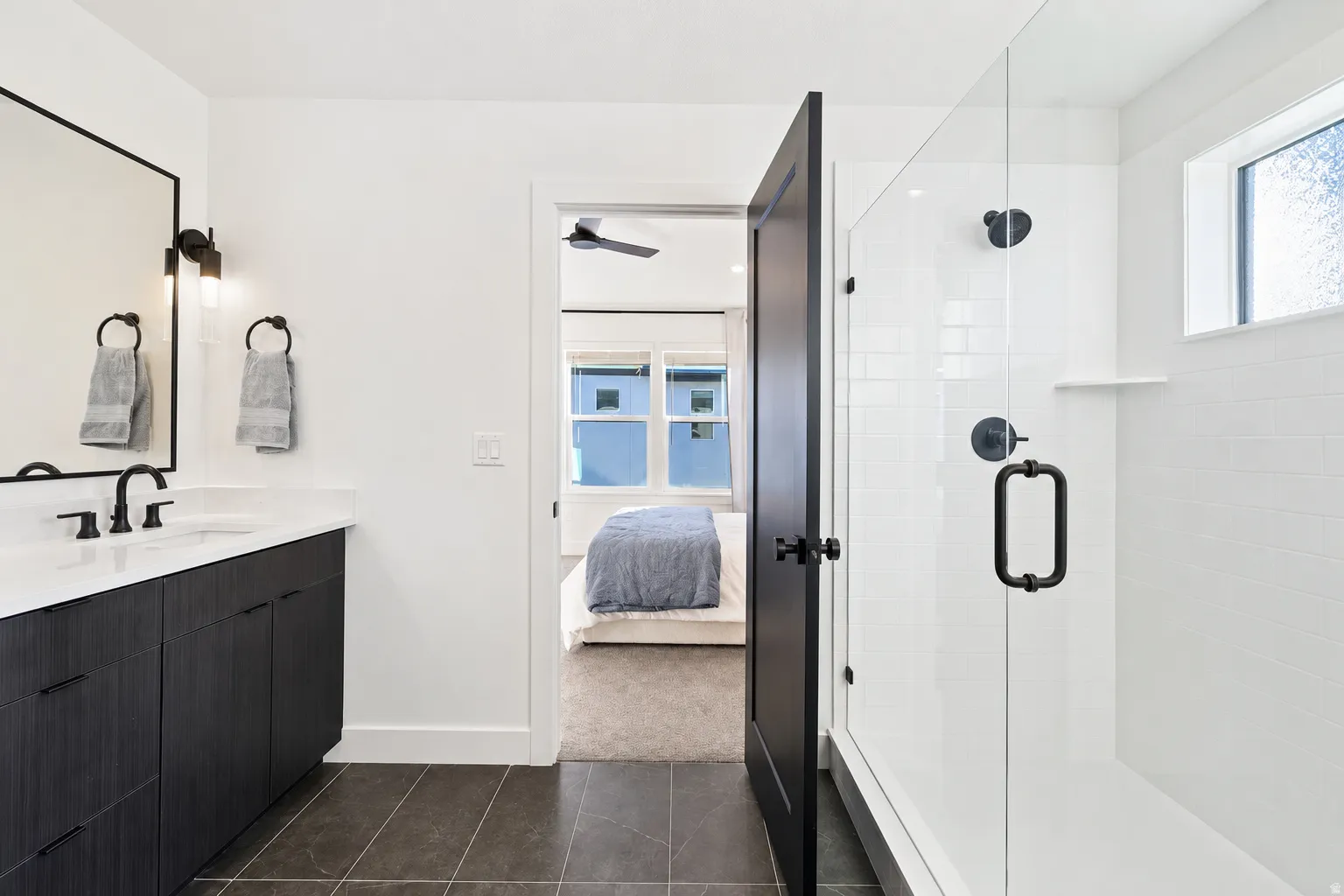 Modern bathroom featuring a single vanity with dark wood-finish cabinetry, white countertop, and black fixtures