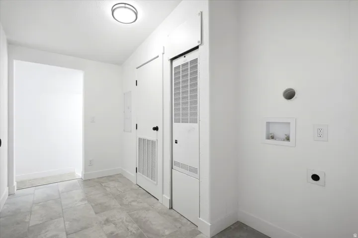 Dedicated utility space featuring tile flooring, a flush-mount ceiling light, and white walls