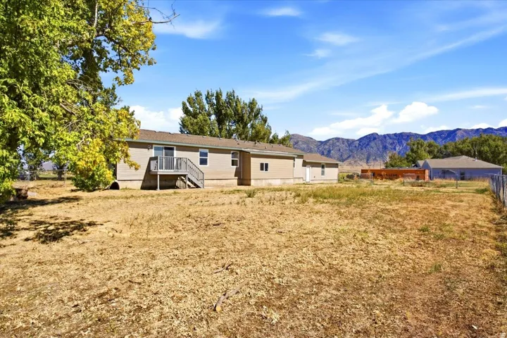 Expansive property featuring a large land area, a tan-sided structure, and a deck with stairs