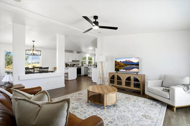 Spacious living area featuring wood-finish flooring, a modern ceiling fan, and white walls