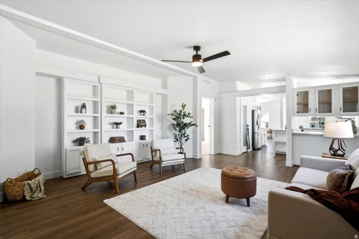 Spacious living area featuring wood-finish flooring, built-in shelving, a ceiling fan, and recessed lighting