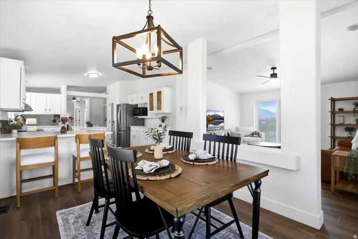 Open-concept living space with wood-finish flooring, white cabinetry, a built-in kitchen island, and a decorative pendant light fixture