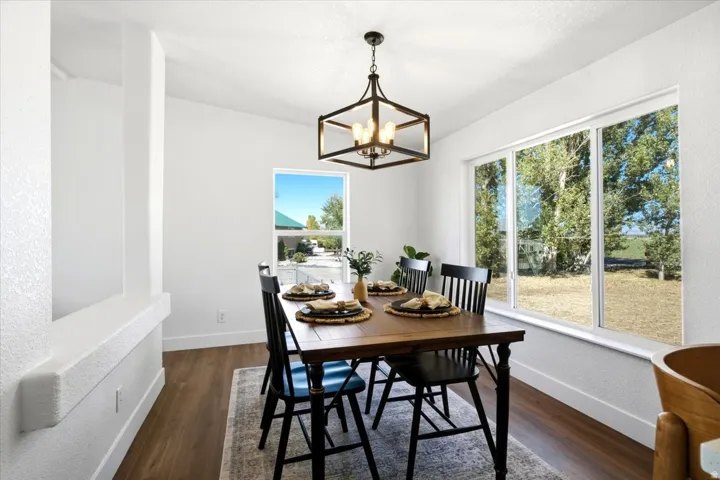 Spacious room with wood-finish flooring, a contemporary chandelier, and large windows