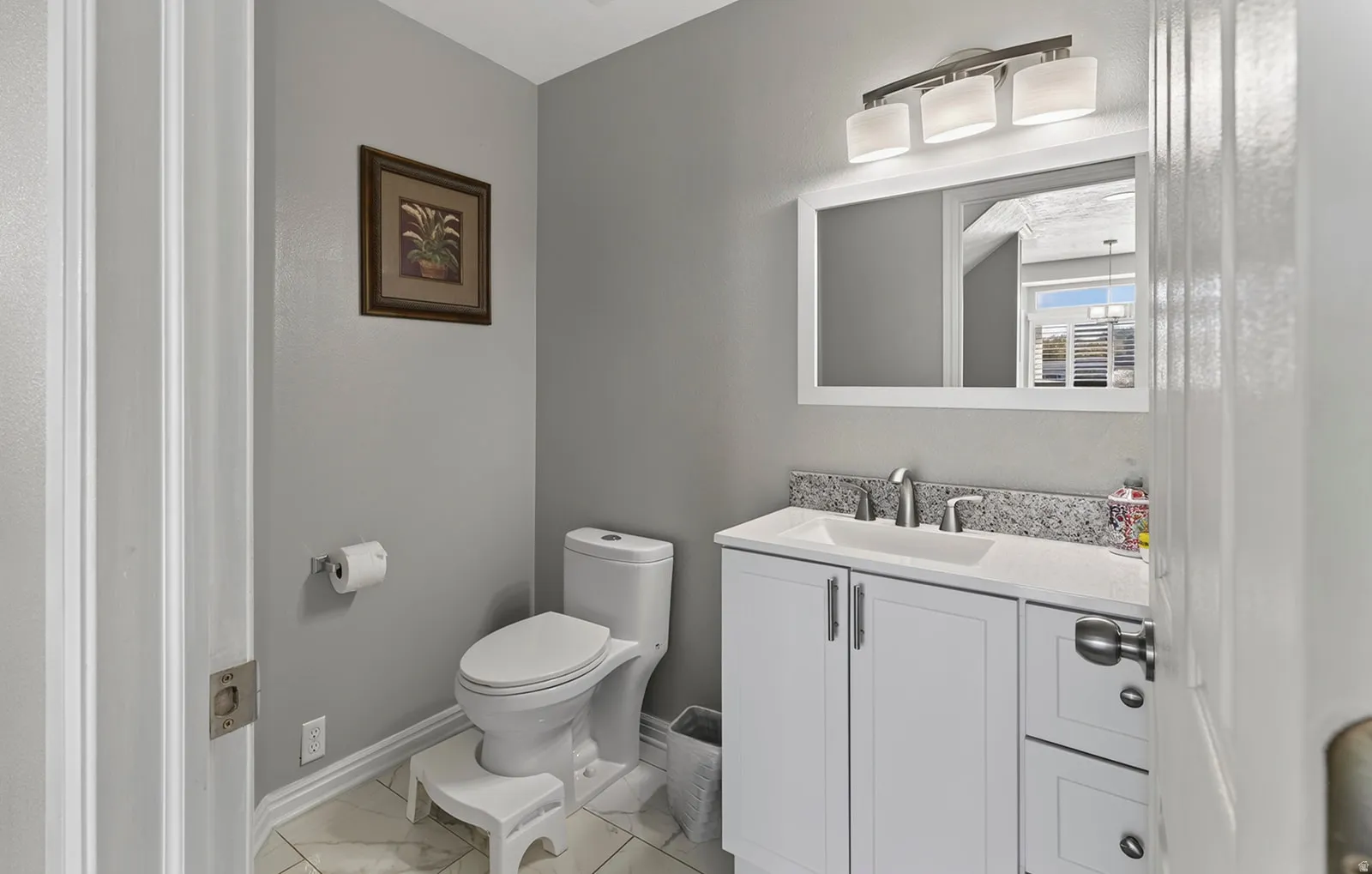 Vanity with a white shaker-style cabinet, integrated sink, and granite-finish countertop