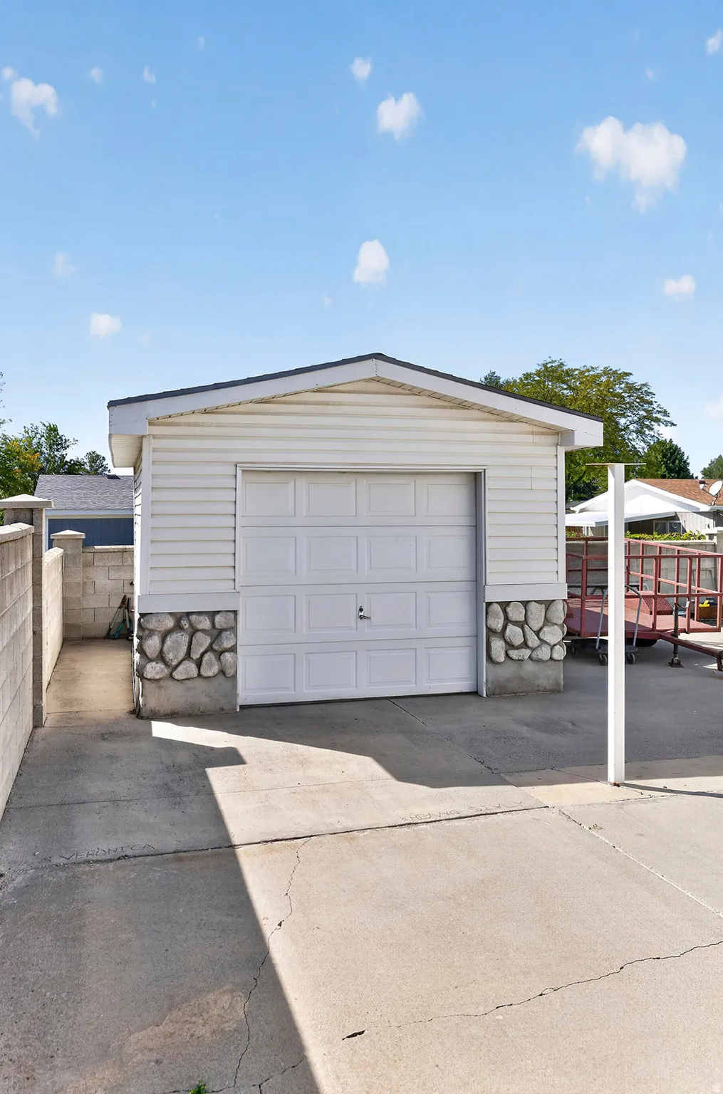 Detached garage with white panel siding and stone veneer accents