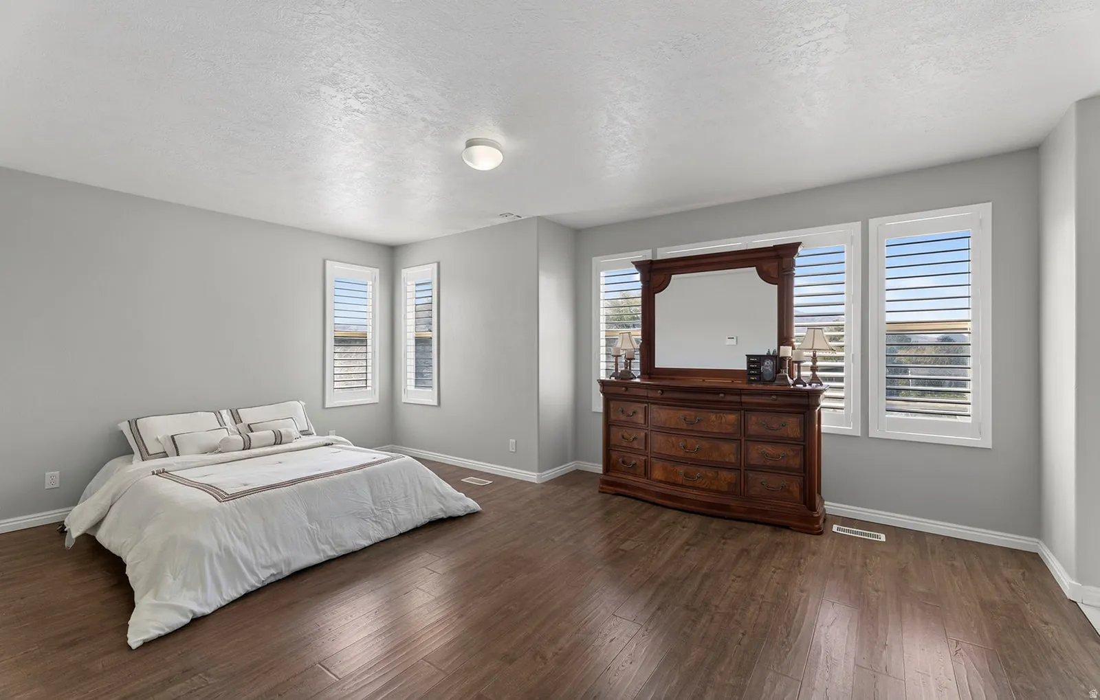 Wood-finish flooring, neutral wall tones, and multiple windows with plantation shutters