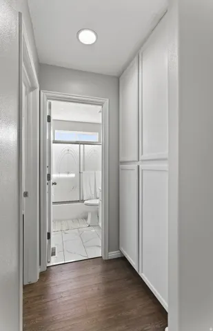 Hallway featuring wood-finish flooring, recessed ceiling light, and built-in white cabinetry