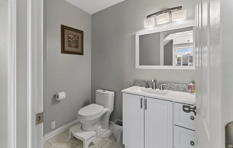 Vanity with a white shaker-style cabinet, integrated sink, and granite-finish countertop