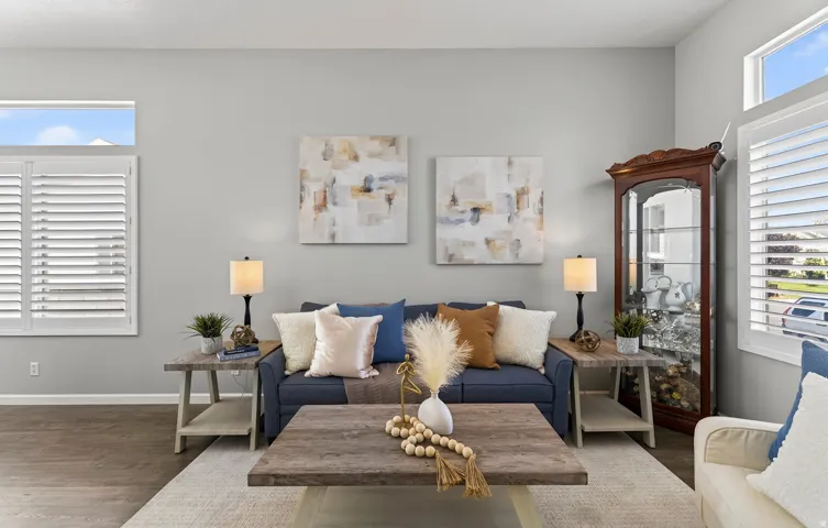 Plantation shutters on multiple windows, wood-finish flooring, light gray wall paint, and a built-in display cabinet
