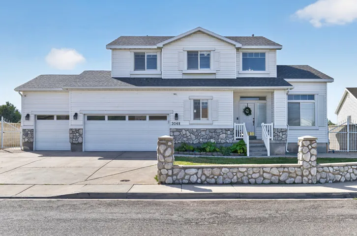 Two-story residence featuring white siding and stone accents