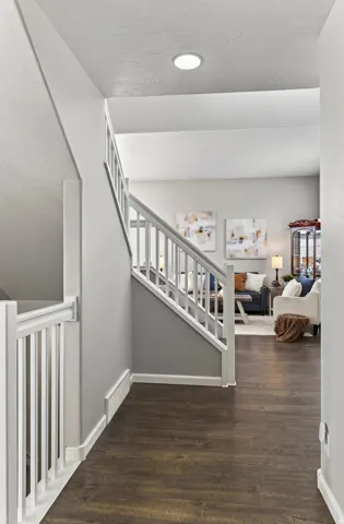 Recessed ceiling lighting, wood-finish flooring, and white painted stair railings