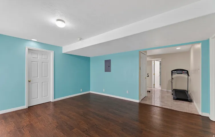 Wood-finish flooring, recessed lighting, and a white six-panel door