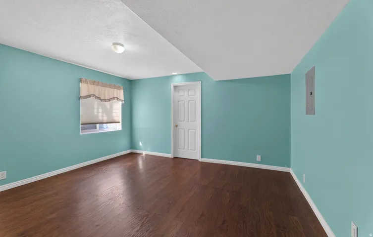 Wood-finish flooring with light blue walls, white trim, and a window with blinds