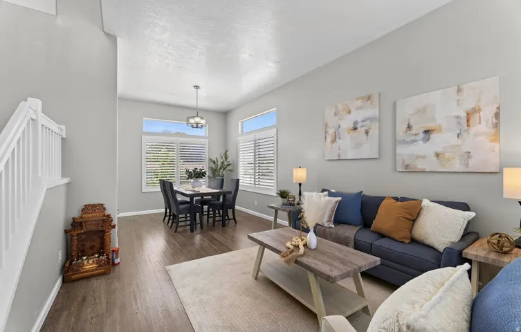 Open-concept living area featuring wood-finish flooring, high ceilings, and plantation shutters