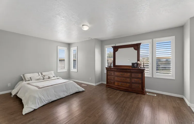 Wood-finish flooring, neutral wall tones, and multiple windows with plantation shutters