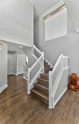 Two-story entry with wood-finish flooring, white spindle stair railing, and a vaulted ceiling