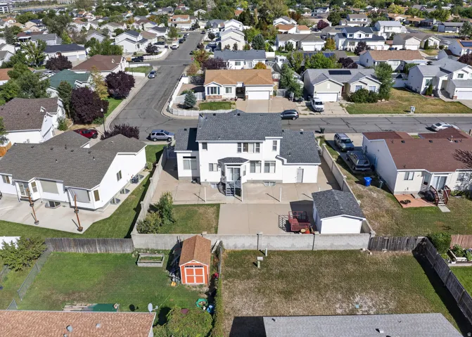 Two-story residence with a gray shingle roof, concrete patio and a detached shed.