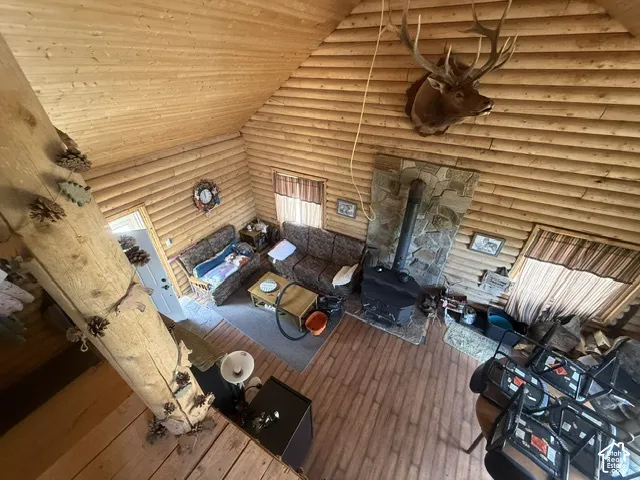 Vaulted wood-paneled ceiling, wood-finish walls, stone-clad wood-burning stove, and wood-finish flooring