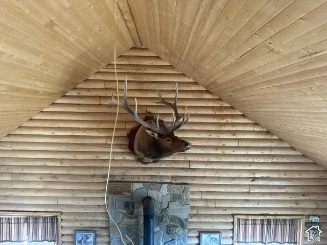 Vaulted wood-paneled ceiling above log-style wall construction