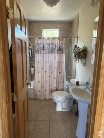 Tiled flooring, pedestal sink, and tiled shower surround with window