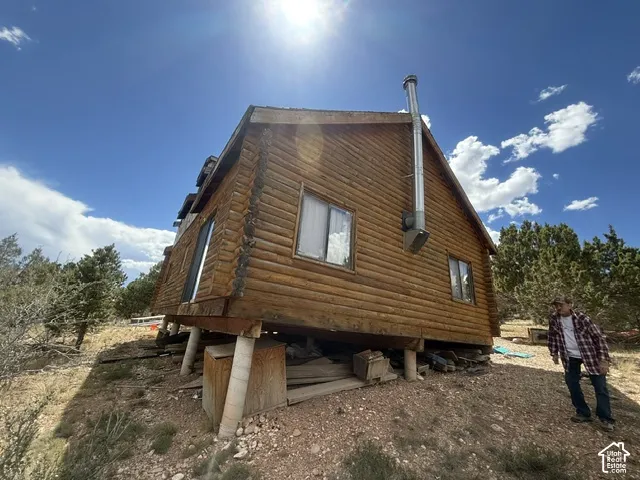 Log cabin construction with a metal chimney and multiple windows