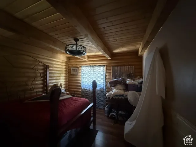Log-style walls with exposed wood beams, wood-finish ceiling, and wood-finish flooring