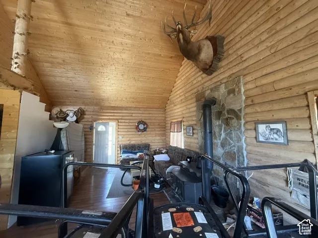 Vaulted wood-paneled ceiling, wood-plank walls, stone-clad fireplace with stove, and wood-finish flooring