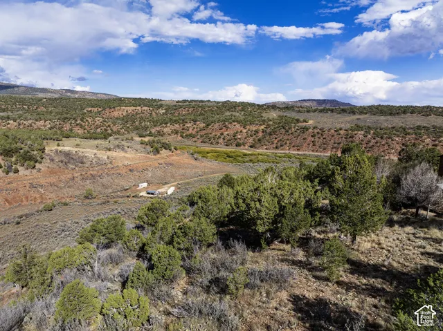 Expansive natural landscape with varied terrain and distant mountains under a blue sky