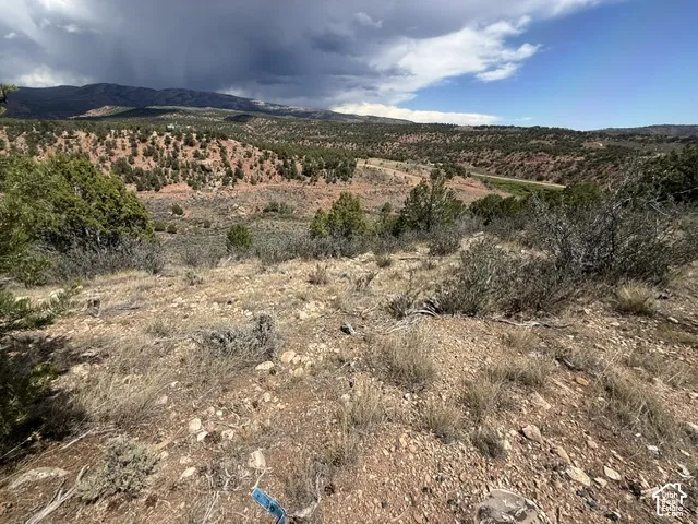 Expansive terrain featuring natural vegetation, distant mountains, and a visible road