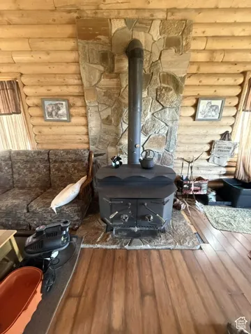 Wood-finish flooring, stone-clad fireplace with wood-burning stove, natural log wall construction