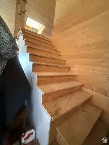 Wood-finish wall paneling, natural wood staircase, and an upper-level skylight