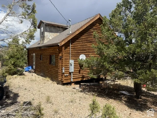 Log cabin exterior with an exposed timber construction, a stone-clad chimney feature, and a sloped roof