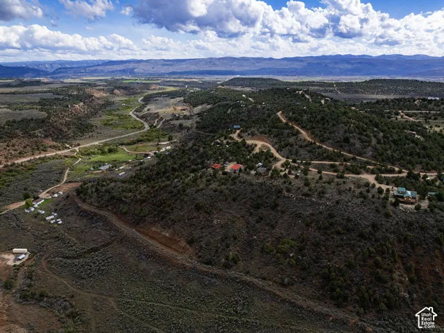 Expansive acreage featuring multiple structures, unpaved roads, and a verdant valley