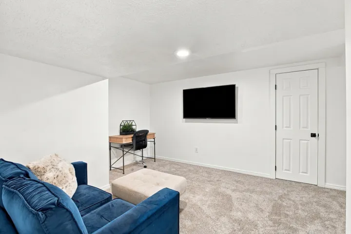 Recessed lighting illuminates the carpeted flooring and white walls