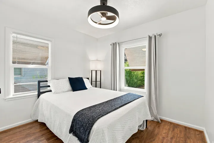 Wood-finish flooring, white walls, two windows, and a ceiling-mounted light fixture