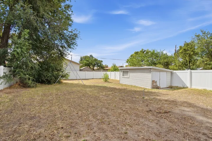Expansive yard with privacy fencing and a detached storage shed