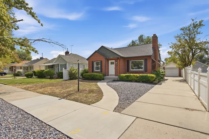 Brick exterior home with a gabled roof, paved driveway, and detached garage