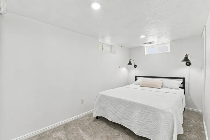 Recessed ceiling lighting, two wall-mounted sconces, and neutral tone carpeting