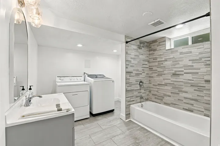 Full bathroom with a built-in tub/shower combination, featuring horizontal tile work