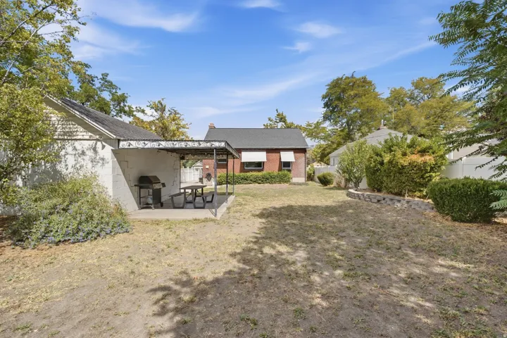 Detached structure with a covered patio, concrete slab, and brick retaining wall