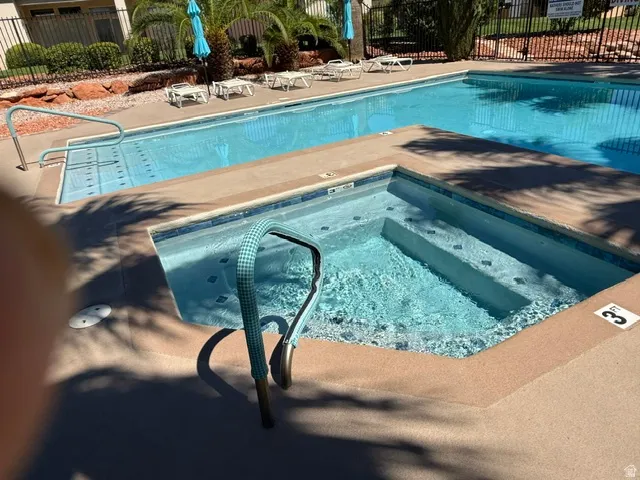Outdoor pool area featuring a rectangular swimming pool, an integrated spa with steps, and a concrete deck