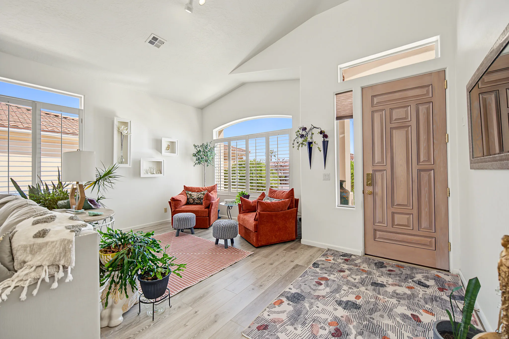Wood-finish flooring, white walls, and vaulted ceilings with track lighting