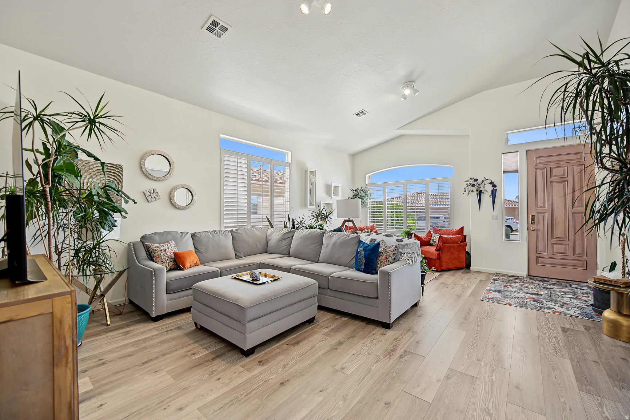 Vaulted ceilings, wood-finish flooring, plantation shutters, arched windows, and a panel-style entry door