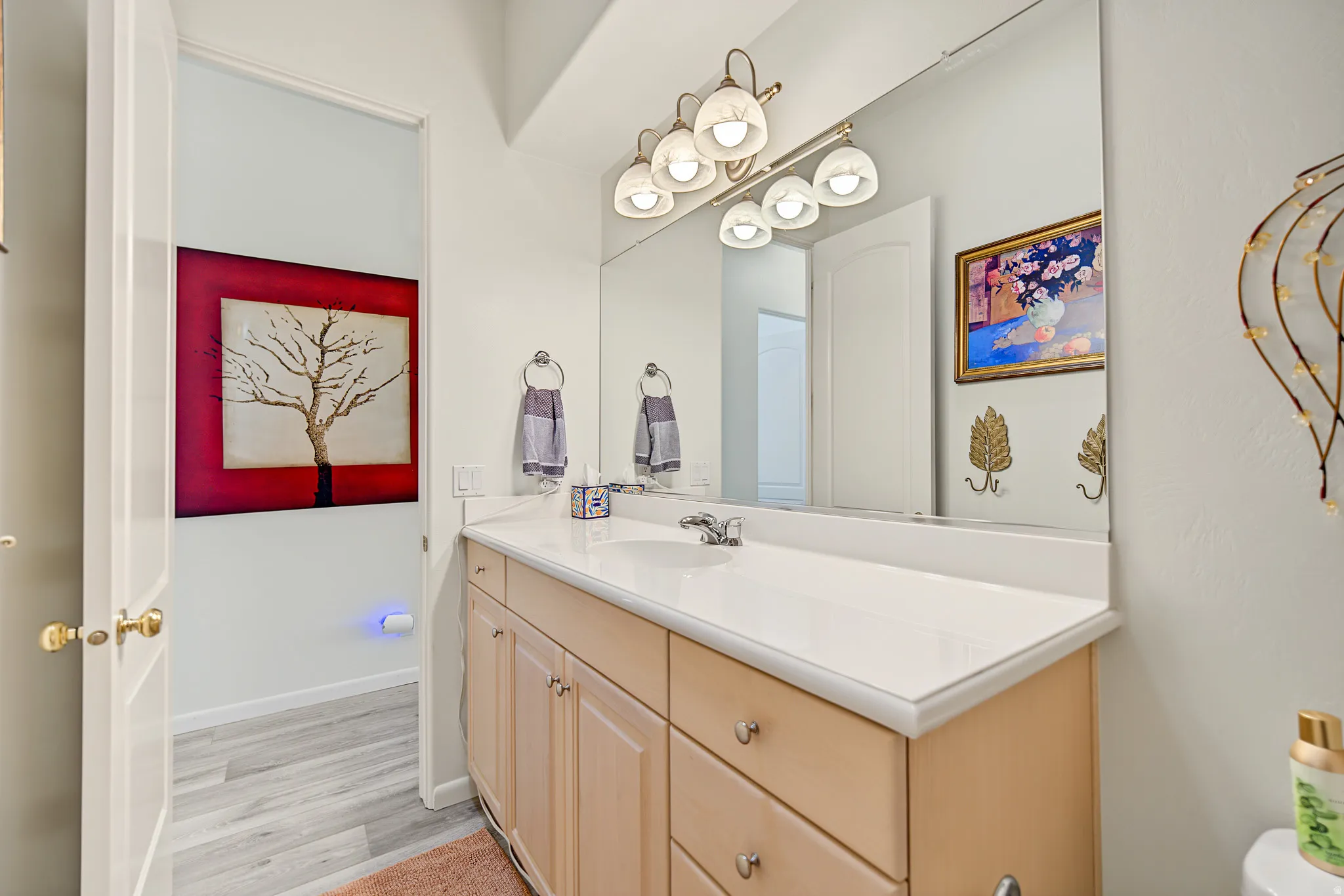 Light-toned wood-finish vanity with a light-colored countertop, an integrated sink, and an overhead five-light fixture