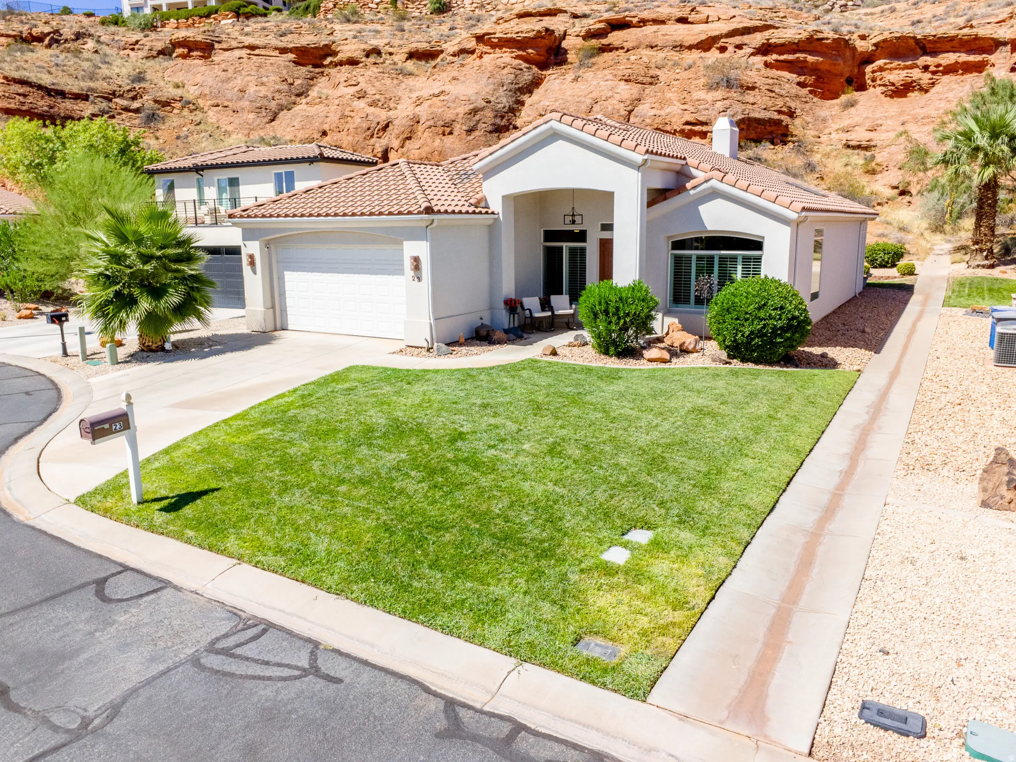 Stucco exterior with a tile roof, two-car garage, and a lush front lawn