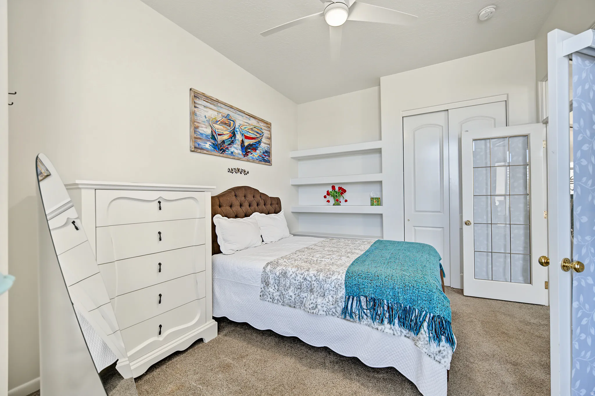 Vaulted ceiling with a ceiling fan, built-in shelving, carpeted flooring, and a closet with sliding doors